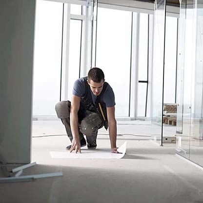 Professional architect laying out a floor plan on the floor of his workspace
