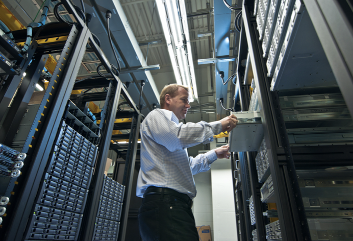 Data center technician working on a server inside a server cabinet